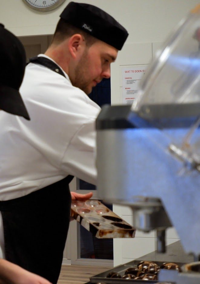Bakker in de opleidingskeuken met een bakplaat in de hand